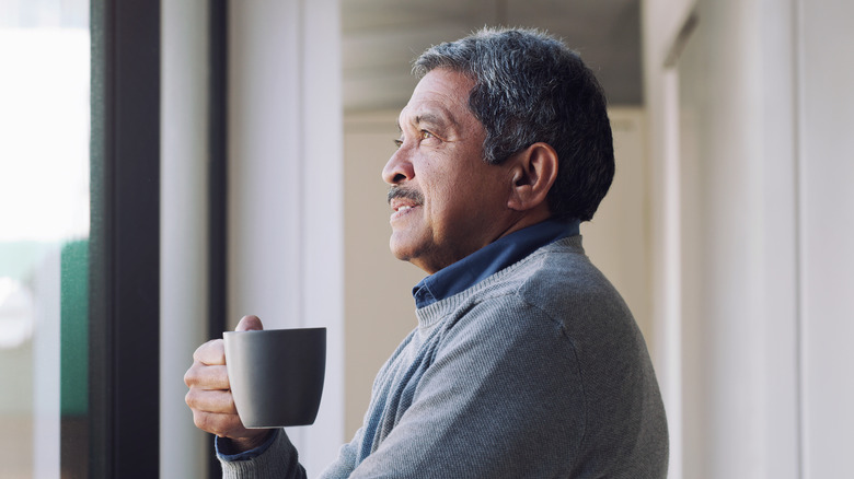 older man holding cup of coffee