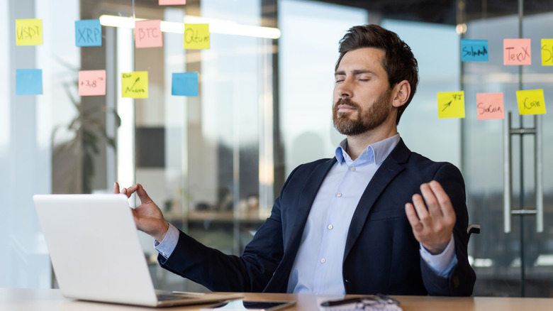 A businessman at his desk meditating and focused