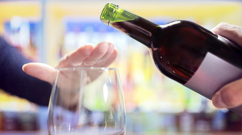 A person refusing to have any wine poured into their glass