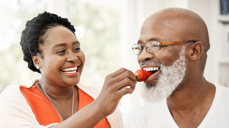 woman feeding man a strawberry