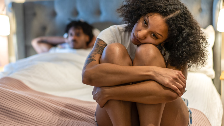 Woman sitting on bed ignoring partner