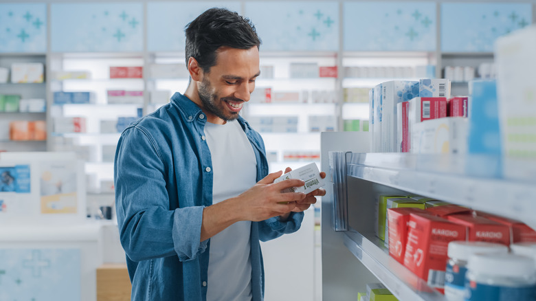 man looking at box of medicine at the pharmacy