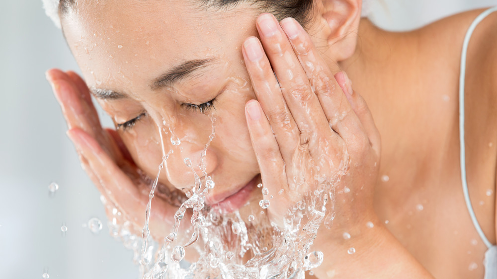 woman rinsing face with water