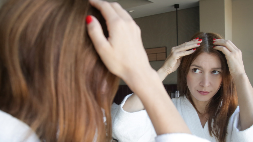 Woman examines her hair in the mirror