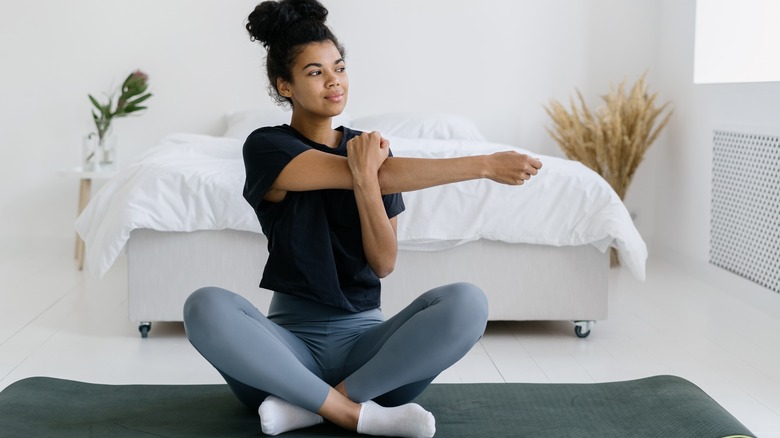 young woman sitting on her mat and stretching before bed 