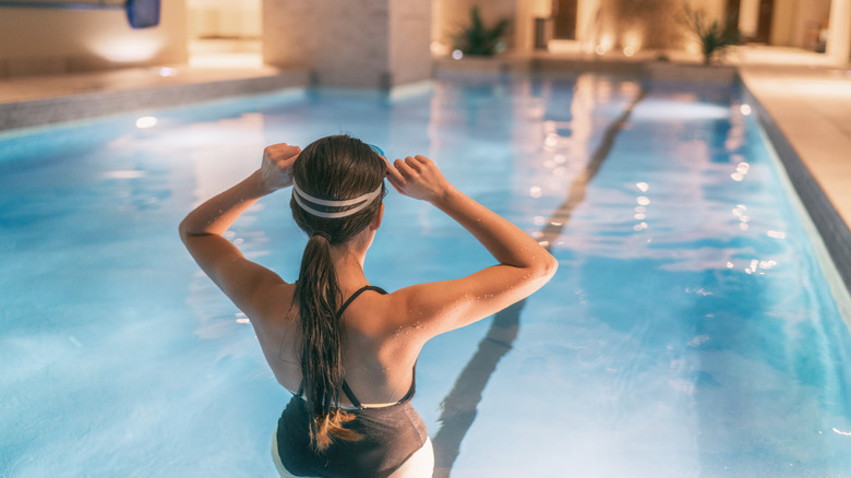 Woman putting on goggles to swim in pool 