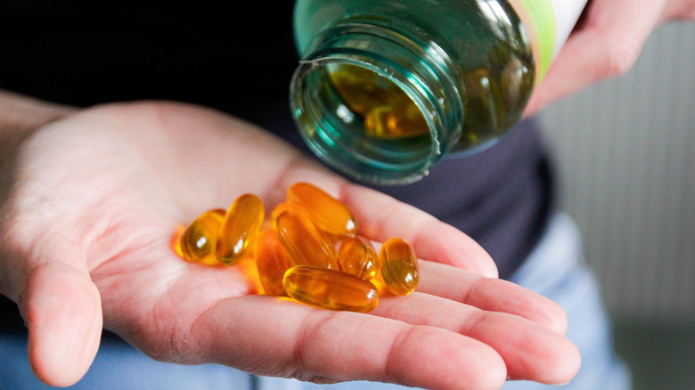 A hand holding several fish oil capsules