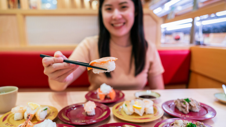 A woman using chopsticks to hold sushi