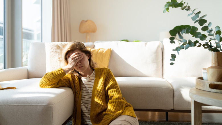 Tired woman with a headache holding her head at home