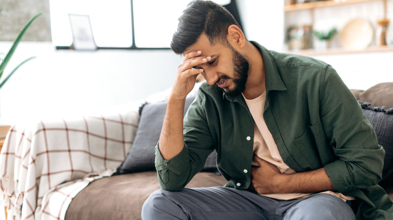 Man sitting on sofa feeling nauseous and unwell