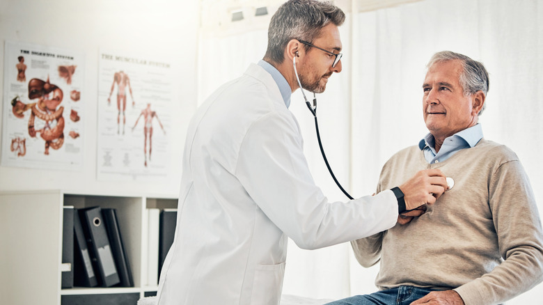 Doctor cheching elderly patient's heart