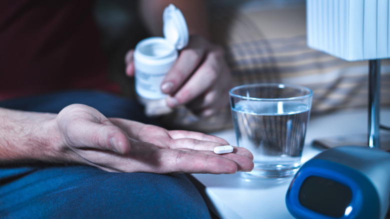 man's hand holding a pill