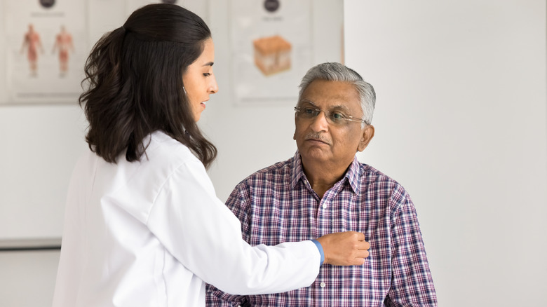A doctor checking the heart of a male patient