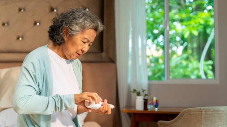 An older woman pouring out supplement tablets onto her hand