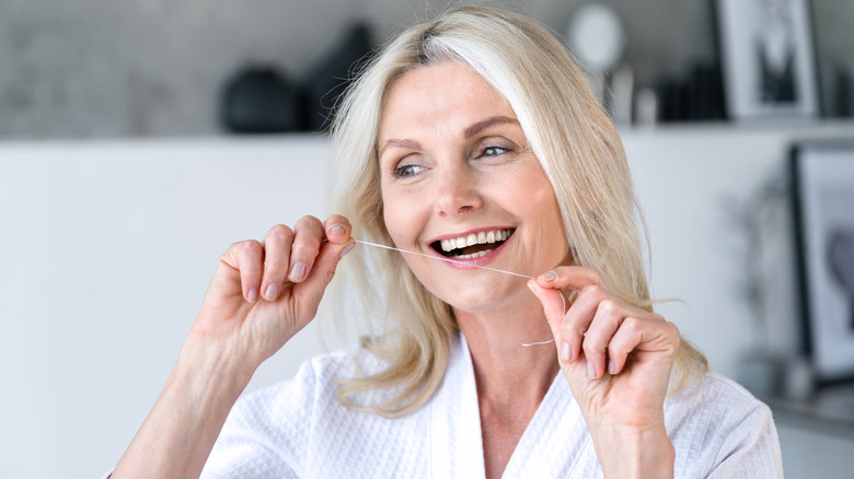 An older woman holding dental floss between her hands