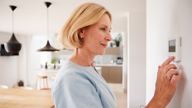 Woman adjusting thermostat