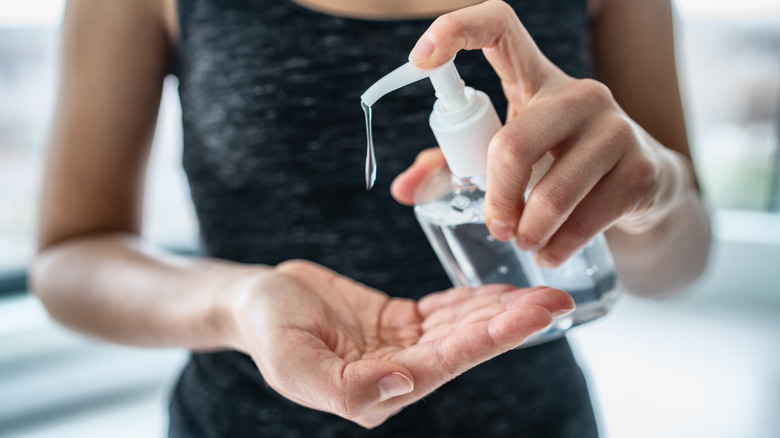 young woman dispensing hand sanitizer from a bottle 