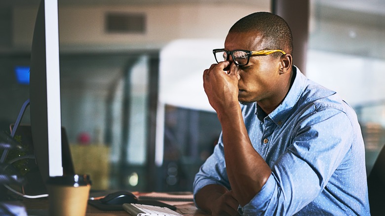 Person with glasses rubbing eyes