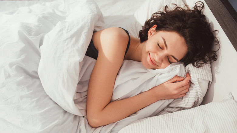 woman smiling in bed holding pillow
