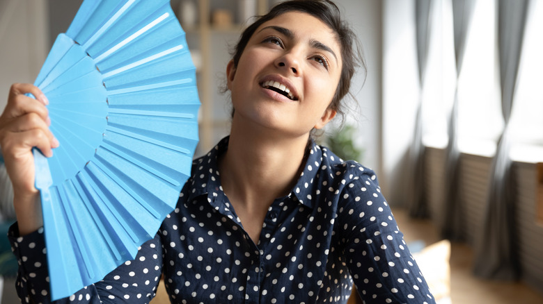 woman cooling herself with fan