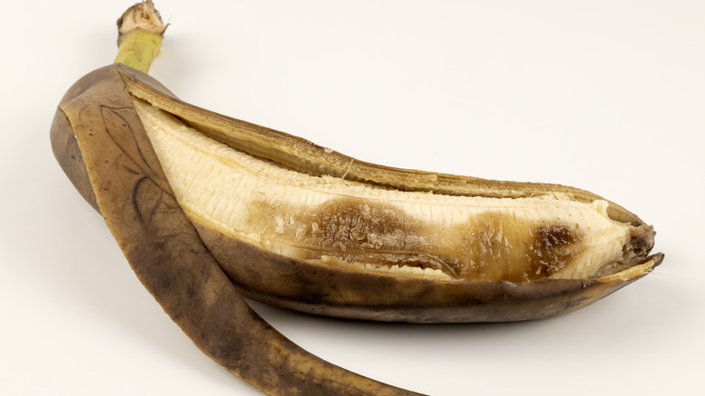 An overripe banana on a white surface
