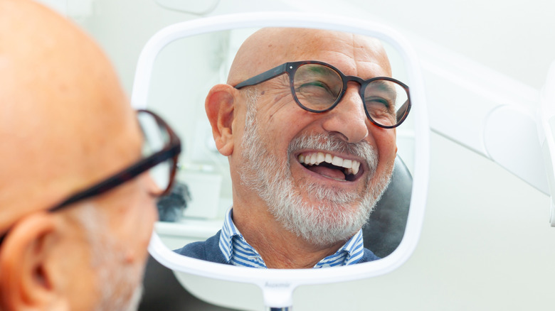 man smiling and laughing while looking in mirror