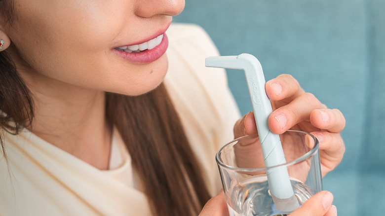 Woman holding HiccAway straw in glass of water