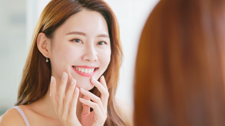 young woman smiling while looking at mouth