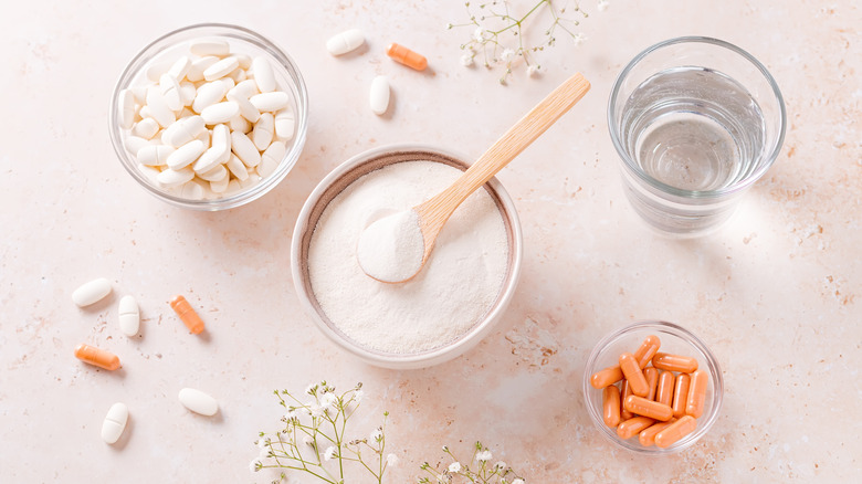 Collagen powder, pills and glass of water on beige stone table top
