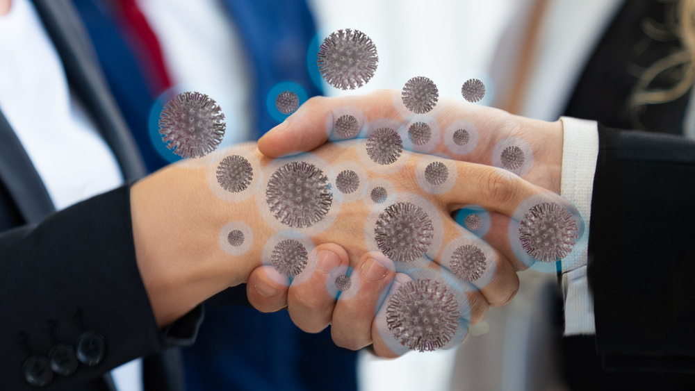 Two people shaking hands spreading COVID-19