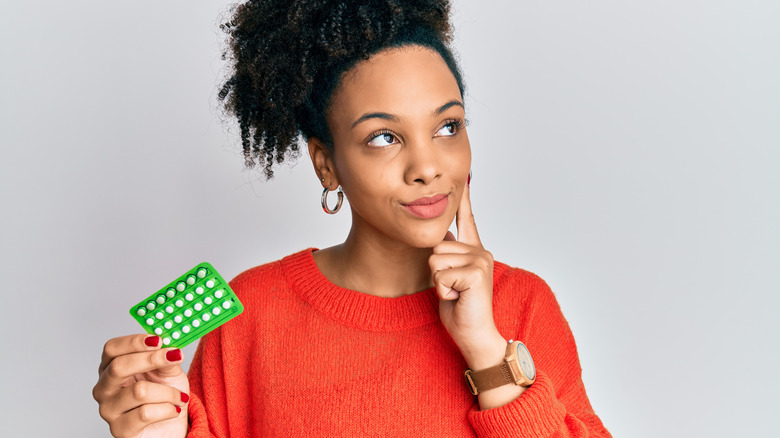 Woman holding birth control pills