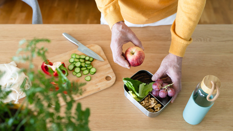 senior woman preparing a healthy apple fruit nut snack