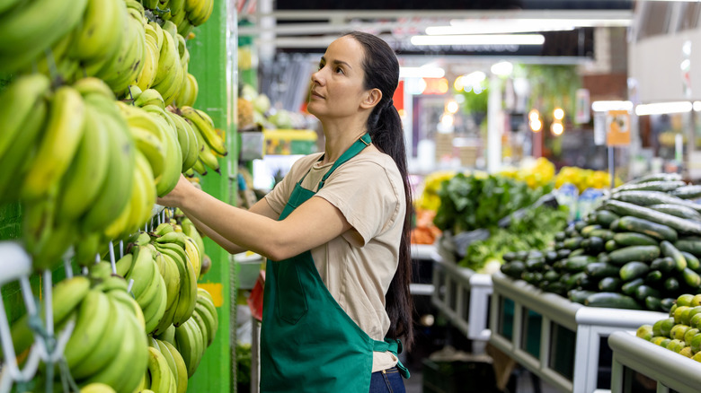 woman working in produce section with bananas in foreground
