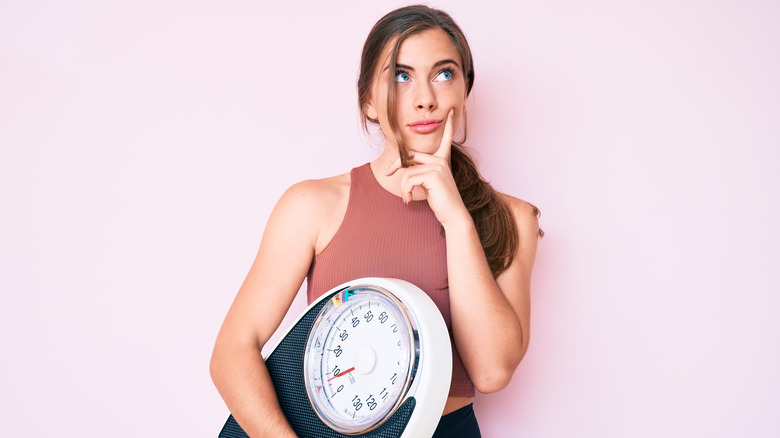 woman holding scale confused