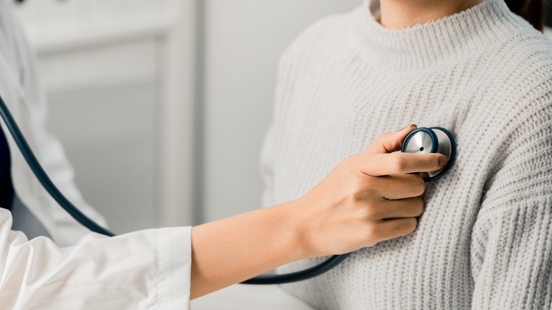 A doctor uses a stethoscope on a woman 