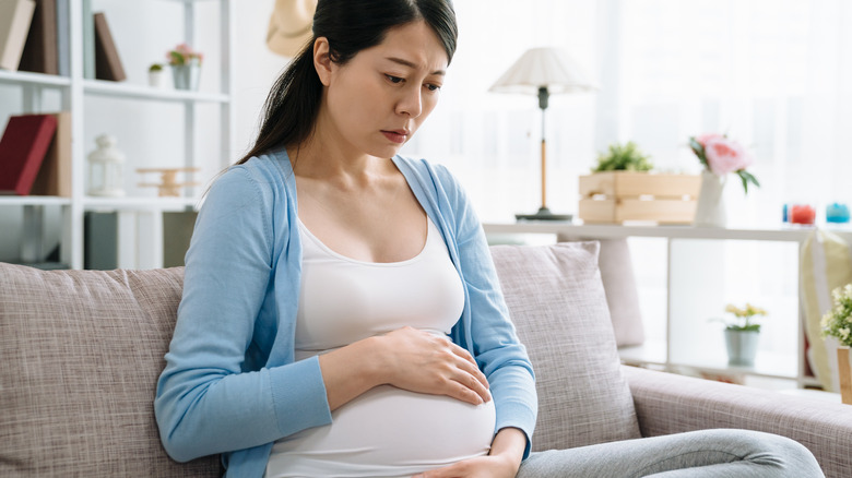 worried pregnant woman holding belly