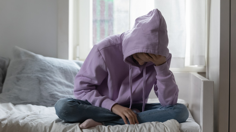 unhappy teenager sitting on bed