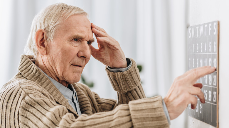 man touching head and calendar