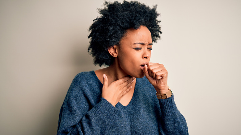 woman coughing into hand