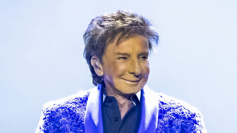 Barry Manilow in a suit, saturated in light, smiling off to the right.