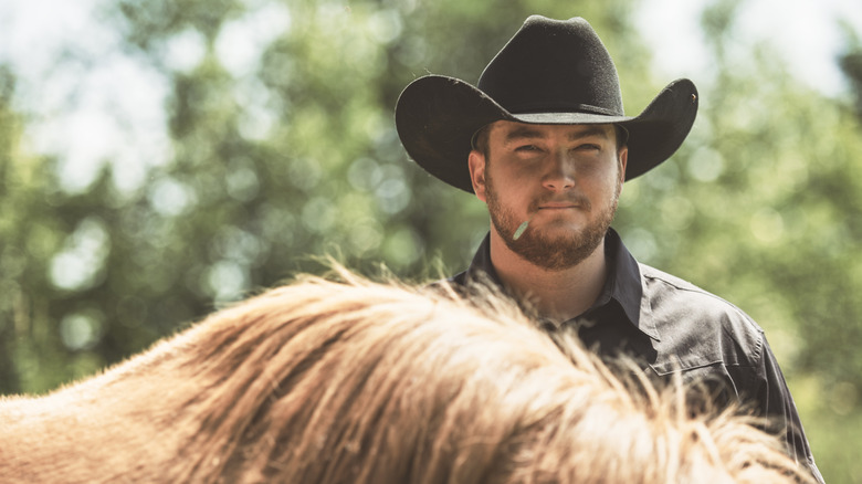 A cowboy standing behind his horse
