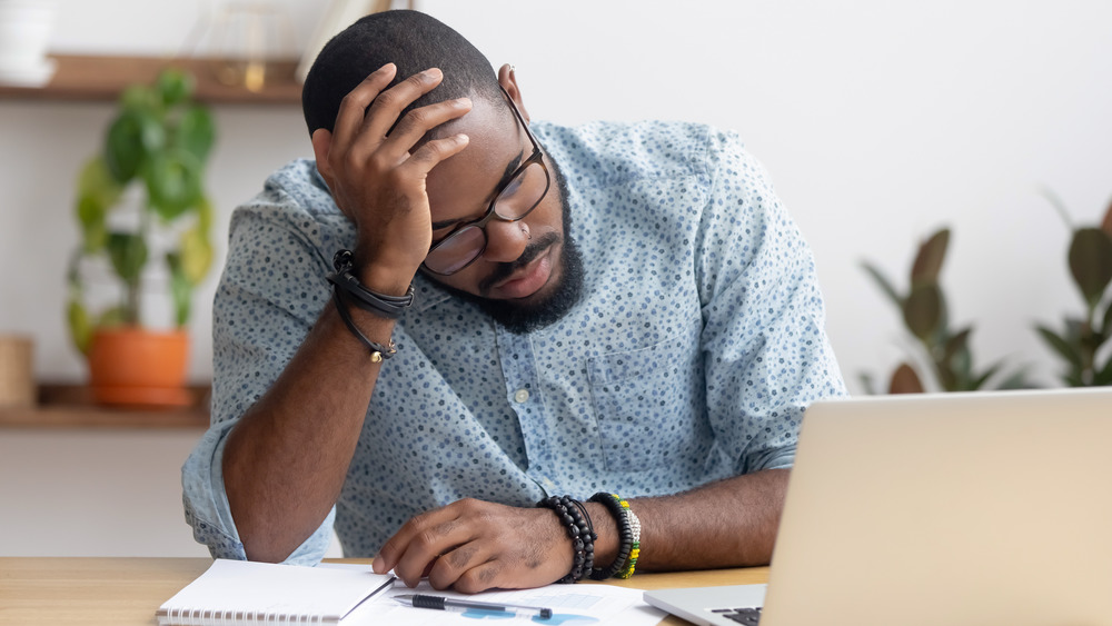 Man holding his head at desk