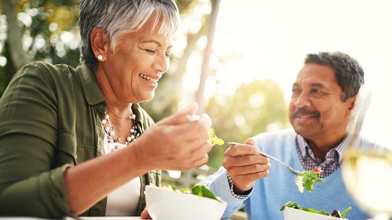 Older smiling couple eating salads