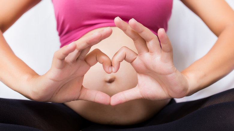 woman making heart around belly button