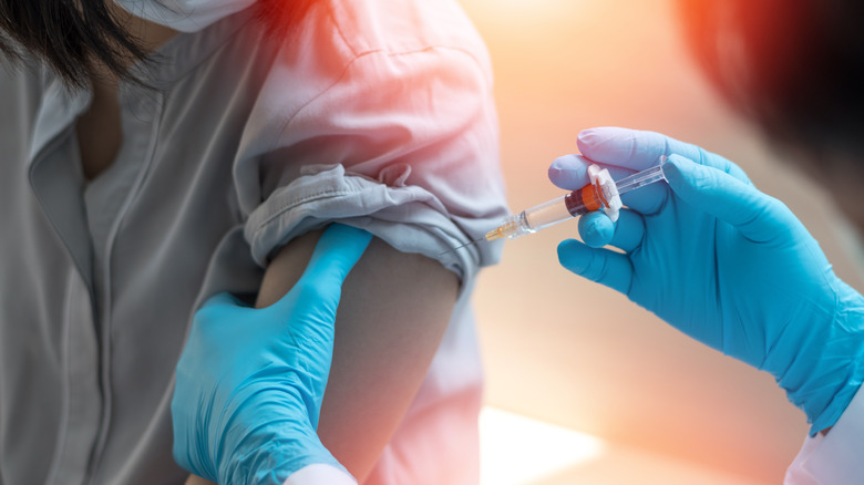 Close up of patient receiving vaccine from gloved hands