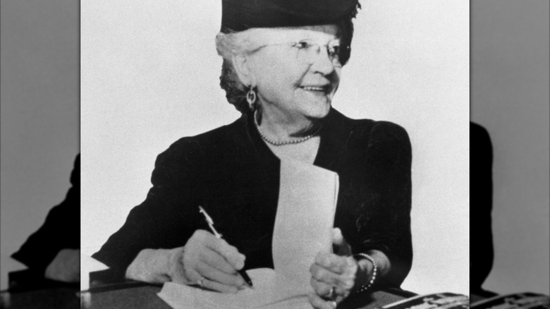 black and white photo of Laura Ingalls Wilder signing a book