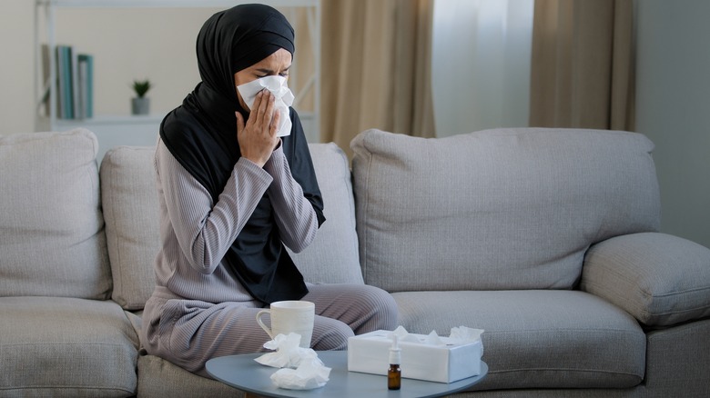 Person sneezing into tissue