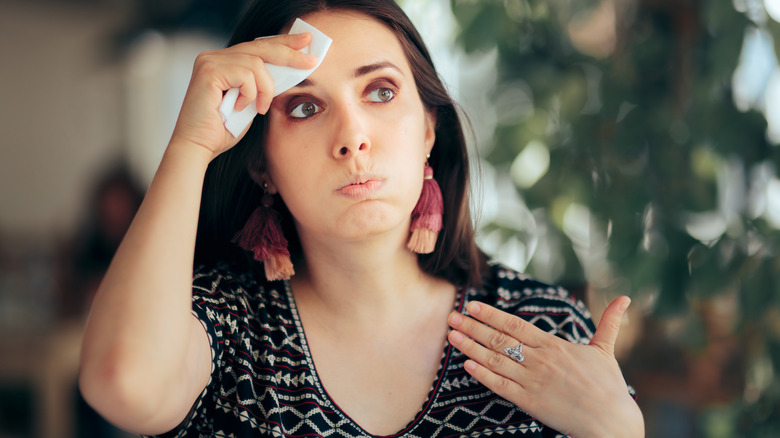 a woman wipes sweat from her brow 