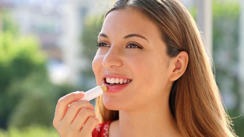 woman applying lip balm while outdoors