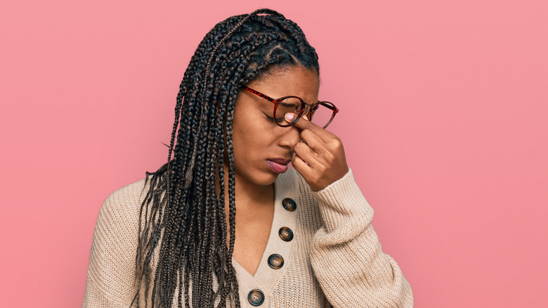 stressed woman pinching face between her eyes